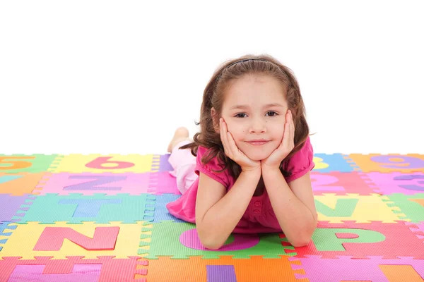 Meisje liggend op alfabet mat — Stockfoto