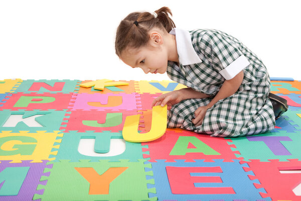 School child in uniform finishing alphabet letter puzzle