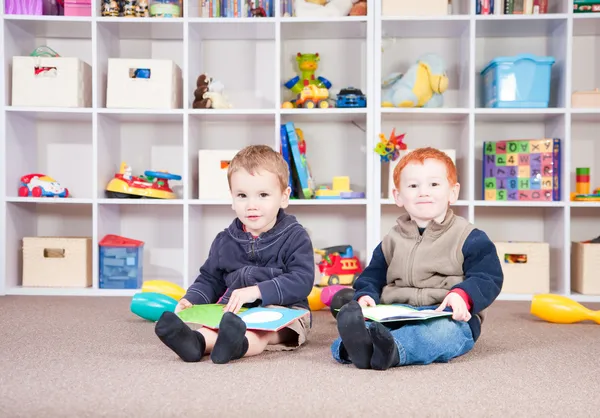 Crianças sorridentes lendo livros infantis na sala de jogos — Fotografia de Stock