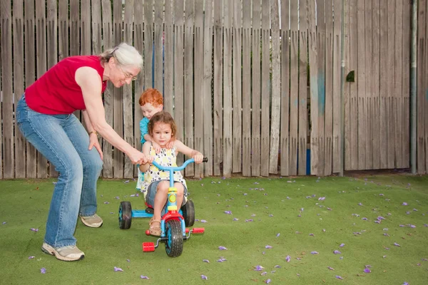 할머니 trike를 타고 아이 들을 돕는 스톡 사진