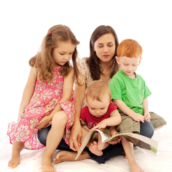 그녀의 무릎에 아이 들에 게 독서 하는 어머니 스톡 사진
