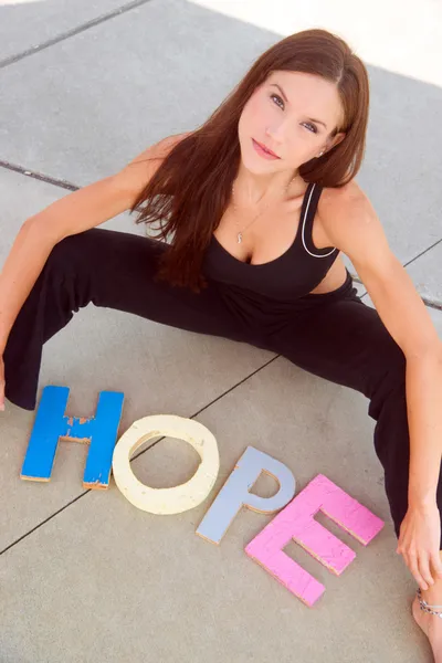 Weibchen zaubern Hoffnung in farbigen Holzblockbuchstaben — Stockfoto