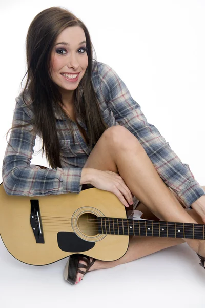 Женщина-музыкант сидит с акустической гитарой улыбаясь — стоковое фото