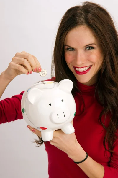 Kobieta zapisuje ćwierć wstawieniem do porcelany piggy bank oszczędzania pieniędzy — Zdjęcie stockowe