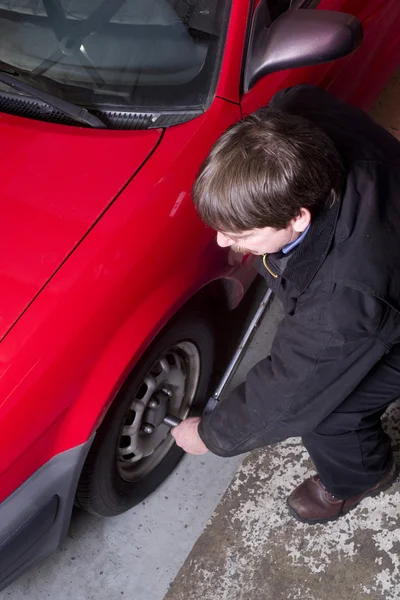 Technicien automobile utilise barre de disjoncteur desserrage écrous sur la voiture — Photo