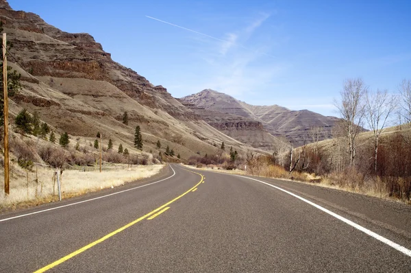 Estrada dividida solitária da estrada de duas pistas corta através da paisagem seca da montanha — Fotografia de Stock
