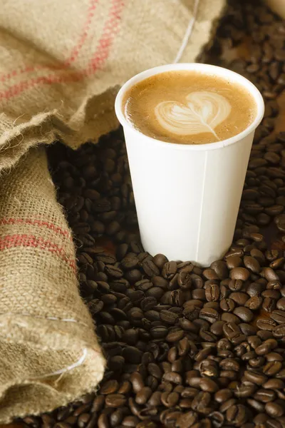 Cappuccino te gaan papieren kopje jute zak geroosterde koffiebonen Stockafbeelding