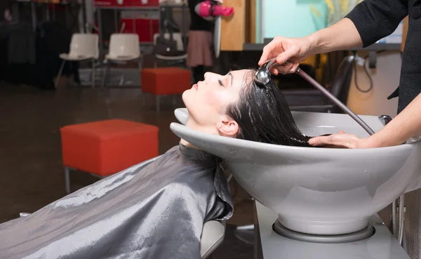 Mooie brunette vrouw laid back wassen station shampoo professional — Stockfoto