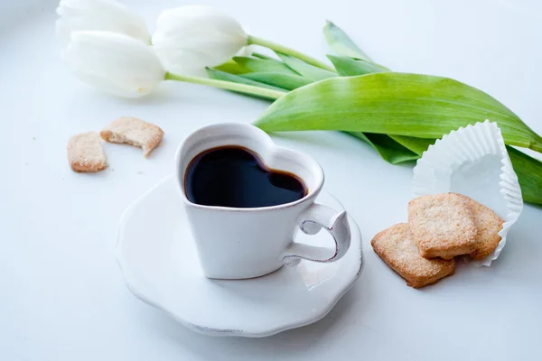 Tasse de café noir avec des cookies et des tulipes blanches sur le fond Photo De Stock
