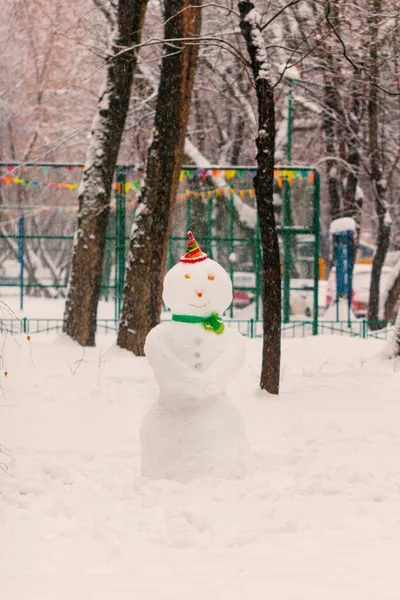 雪の冬の街の庭で幸せな居心地の良い雪だるま — ストック写真