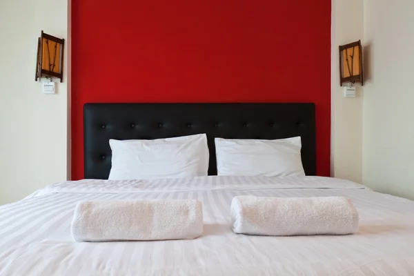 Camera da letto con parete rossa, Asciugamano sul letto . — Foto Stock