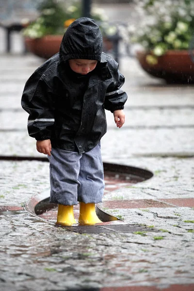 Bambino in stivali gialli sotto la pioggia — Foto Stock