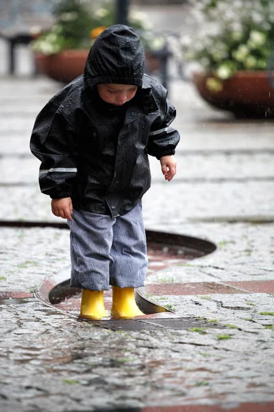 Kind in gele laarzen in de regen Rechtenvrije Stockfoto's