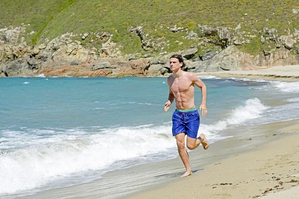 Jeune homme blanc courant sur la plage — Photo