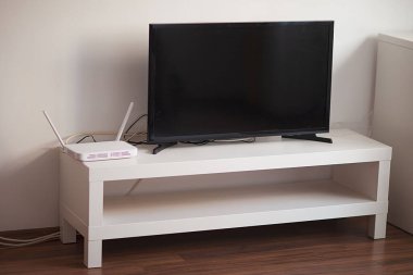 Beyaz bir masanın üzerinde beyaz bir iç kısmının arka planında siyah plazma TV var. seçici odak