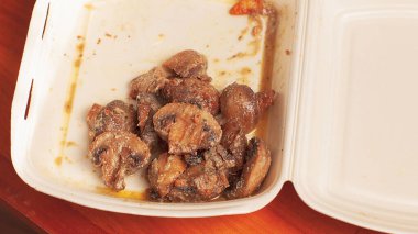 Kahverengi arka planda tek kullanımlık beyaz tabakta pişmiş şampiyonlar.