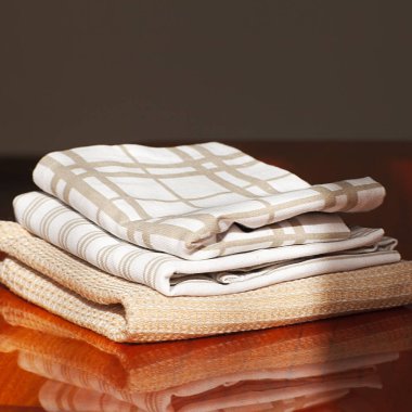 Kahverengi bir masada, kare şeklinde mutfak havluları.. 