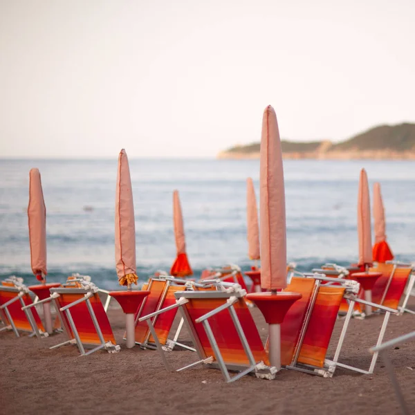 Sun beds and colorful folding umbrellas on the beach. sand, dawn, coast, horizon, sea.