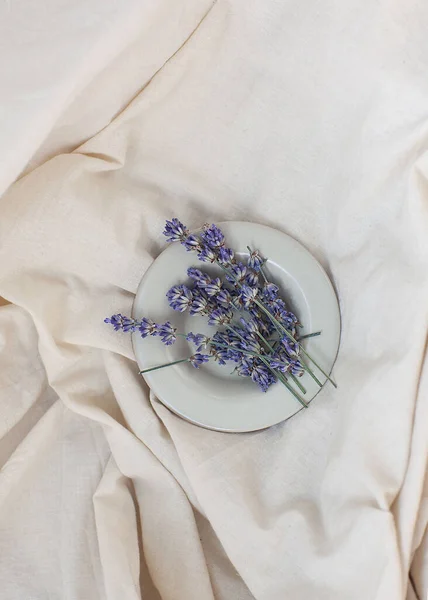 Sprigs of lavender and lavender flowers in a cream bowl on a white background with copyspace. Aromatherapy