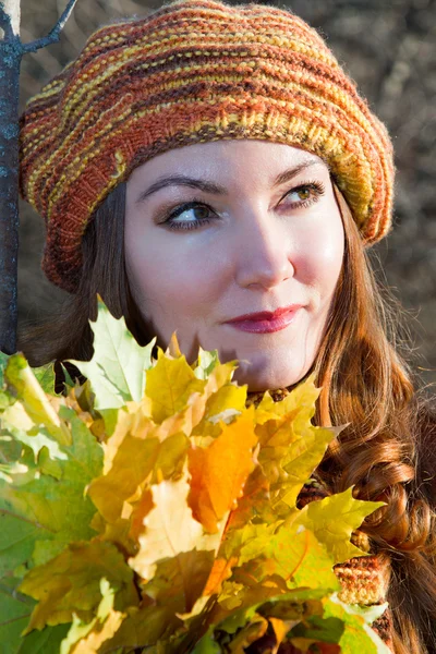 Akçaağaç yaprakları üzerinde nat ile örme bere sonbahar kadının portresi yukarıya kapatmak — Stok fotoğraf