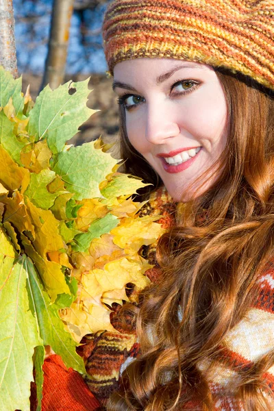 Крупный план портрета осенней женщины в трикотажном берете с кленовыми листьями на нате — стоковое фото