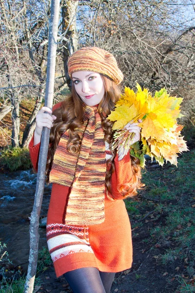 Beautiful woman in knitted clothes in a full-length with a bouquet of maple — Stock Photo, Image