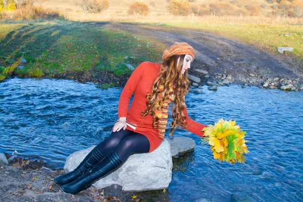 Krásná dívka s dlouhými kudrnatými vlasy do Pletené oděvy obsazení javorový list — Stock fotografie