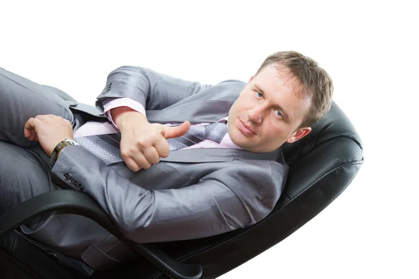 Homem de sucesso em um terno de negócios cinza mostra um positivo em uma cadeira no w — Fotografia de Stock