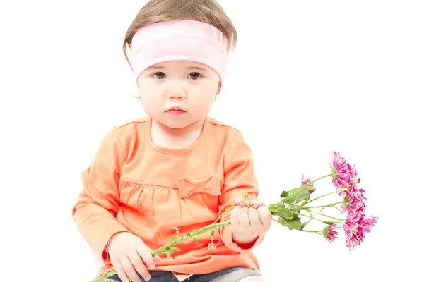 Menina bonito pequeno bebê com flores para a mãe no fundo branco — Fotografia de Stock