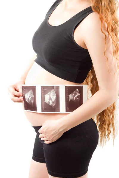 Zwangere vrouw s buik met de echografie beelden in de handen van een witte b — Stockfoto