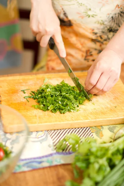 Woman s hands cutting fresh onions, dill, parsley on kitchen Focus on gree — Stock Photo, Image
