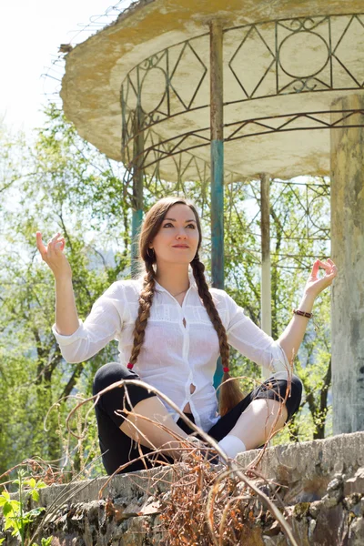 Mujer hermosa con el pelo largo meditando cerca de la arquitectura con columnas, n —  Fotos de Stock