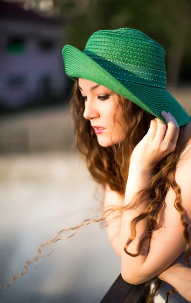Portrait of beautiful young woman in green hat in summer park — Stock Photo, Image
