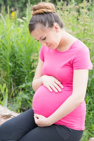 Gelukkig zwangere vrouw met grote buik rest op aard — Stockfoto