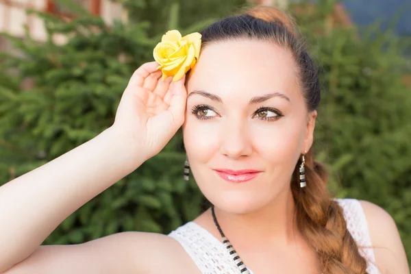 Portret van mooie jonge vrouw met gele bloem op lange haren op natur — Stockfoto