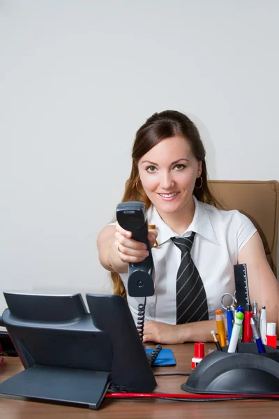 Happy office worker girl on landline phone call, listening to conversation in an office environment. — Stock Photo, Image