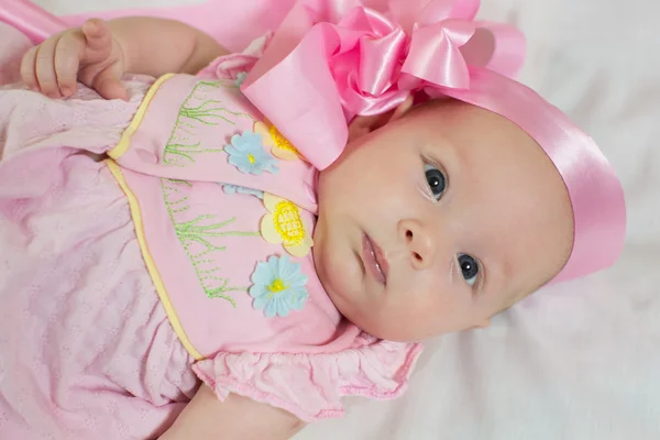 Roztomilý malý novorozeně dívka v růžových luk a oblečení na postel — Stock fotografie