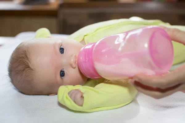 Bebé recién nacido con un biberón de leche. El concepto de alimentación y crianza —  Fotos de Stock
