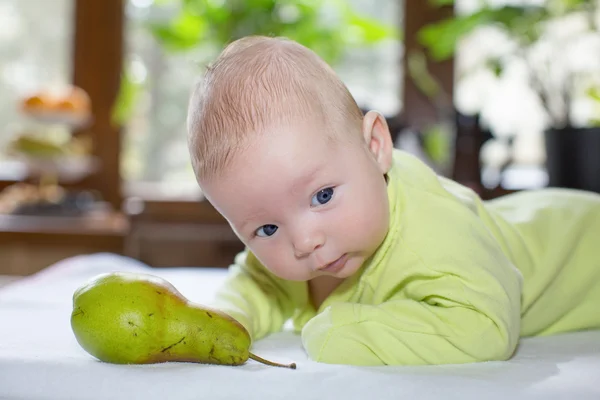 Yeni doğan bebek kız ile bir meyve armut ile. Gıda ve ebeveynlik kavramı — Stok fotoğraf