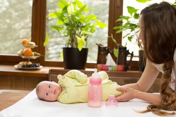 Bébé fille nouveau-né avec une bouteille de lait et sa mère . — Photo