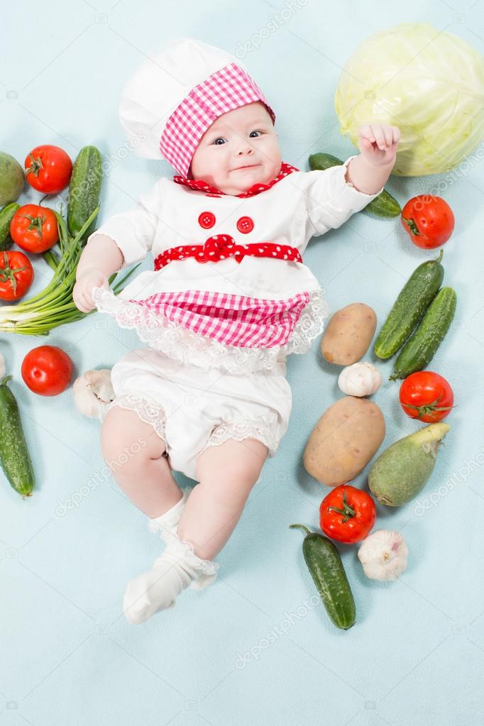 Gülen bebek sebze tarafından çevrili bir aşçı şapkası portresi. bir