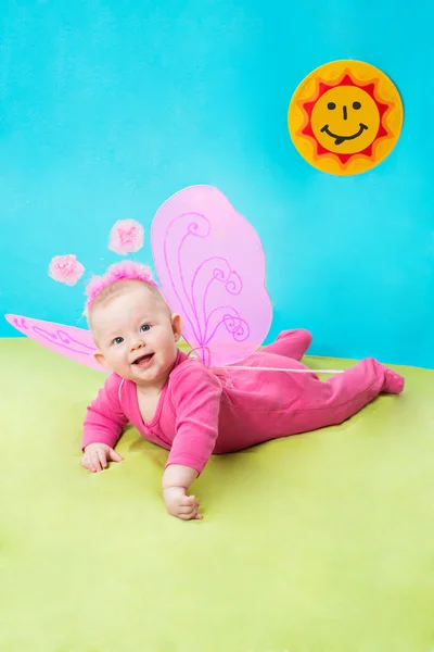 Pretty child girl, dressed in butterfly costume on green background and sun. The concept of childhood and holiday — Stock Photo, Image