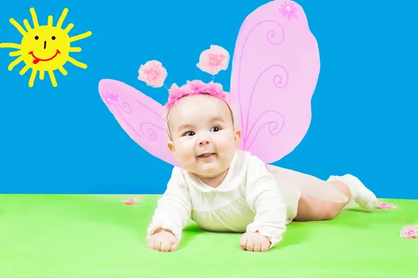 Pretty child girl, dressed in butterfly costume on green background and sun — Stock Photo, Image
