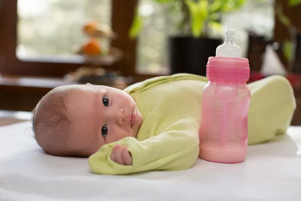 Bebé recién nacido con un biberón de leche. El concepto de alimentación y crianza — Foto de Stock