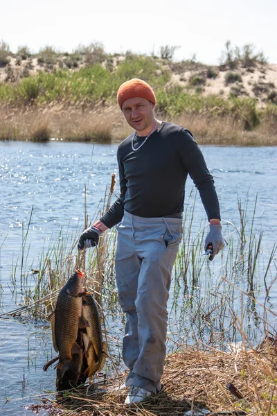 Lycklig lycklig fiskare håller en stor karp på floden. tidigt på morgonen på fiske — Stockfoto