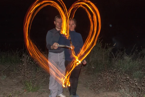Ευτυχισμένο ζευγάρι ζωγραφική η καρδιά φλόγες της φωτιάς ως ένα σύμβολο της αγάπης και οικογένεια νύχτα — Φωτογραφία Αρχείου