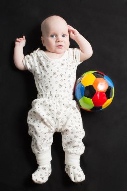 siyah arka plan üzerine futbol topuyla oynayan bebek. Bebekler ve çocuklar