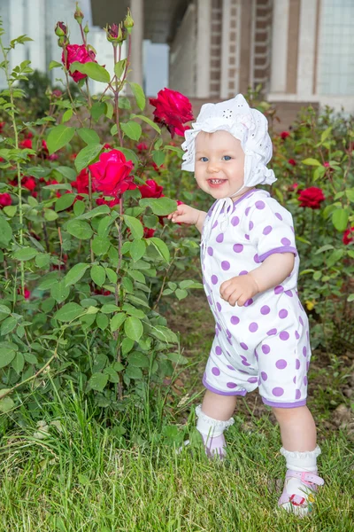 Sorridente graziosa bambina con fiore rosa nel parco — Foto Stock