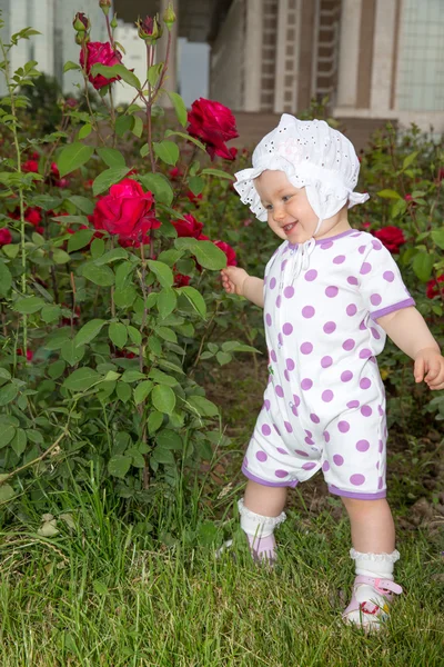 Sonriente niña bonita con flor rosa en el parque —  Fotos de Stock