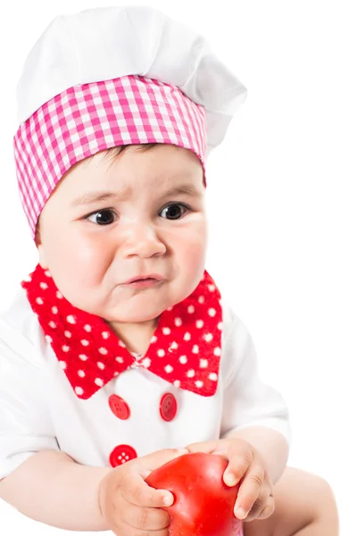 Bebé con un sombrero de chef con tomate aislado sobre fondo blanco.El concepto de comida saludable y la infancia — Foto de Stock